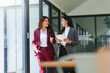 © Crystal - Two Asian businesswomen discussing work while walking outside a modern office building, one holding a digital tablet