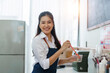 © Crystal - Young Asian woman barista in apron smiling, making drinks in a cafe. Concept of small business owner and entrepreneurship