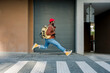 © Westend61 - Cheerful man in casual clothes jumping with backpack on urban street