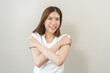 © KMPZZZ - Smiling positive, hug self care happy asian young woman hands hugging herself shoulders, enjoy yourself, self love and self care, smile girl face expression self esteem standing isolated on background
