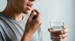© felasteri - Close up of a person taking a vitamin capsule with a glass of water emphasizing health and wellness routines