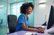 © Pete - Smiling African American woman works on computer in modern medical clinic office. Types on keyboard, uses mouse, manages patient info, appointments. Happy professional helps clients efficiently,
