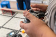 © ako-photography - Hands using a game controller to operate a robot in a technology workshop