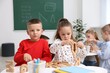 © New Africa - Cute children at white tables during lesson in elementary school