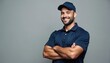 © Pete - Smiling man wears navy polo shirt and cap. He stands with arms crossed against a plain gray backdrop, exuding confidence. Pro worker ready for service tasks.
