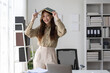 © Wasan - Cheerful Asian businesswoman holding a notebook and smiling in the office.