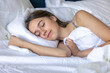 © puhimec - Girl falling asleep with a soft smile under white duvet. Peaceful sleep.