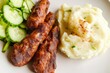 © Konstiantyn Zapylaie - Delicious grilled sausages with mashed potatoes and sliced cucumbers on a plate