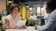 © DC Studio - Hiring manager conducting a detailed job interview with applicant, reviewing the candidate qualifications, CV resume and potential onboarding for career advancement within the company. Camera A.