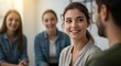 © Image - Focused woman engages in conversation, with smiling women in the background, indoor shot.