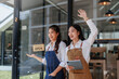 © Crystal - Asian women entrepreneurs greeting and inviting customers inside their open cafe, smiling and working in a small business