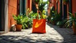 © YULIIA - A stylish orange tote bag placed on a cobblestone path surrounded by lush greenery and colorful planters.