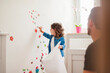 © Westend61 - Father and daughter decorating wall with stickers at home