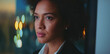 © Videophilia - Young businesswoman with an afro haircut is looking out a window at night, thoughtfully contemplating the blurred city lights, indicating determination and successful future planning