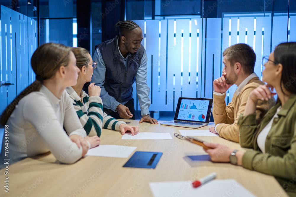 Diverse business team gathered around a table discussing analytics ...