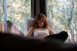 © Laia Balart - Young redhead woman relaxing at cabin using mobile phone to watch a series
