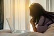 © shine - Concentrated middle aged beautiful asian woman looking at laptop screen while lying on her comfortable bed and browsing on the net with bathed in warm sunlight, creating peaceful work atmosphere.