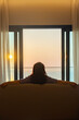 © shine - Vertical photo of Happy woman resting in comfort on sofa at hotel or home living room having lazy free time with peace of mind. Beautiful soft gradient orange gold clouds and sunlight on blue sky.