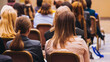 © tsuguliev - Female audience at the symposyum meeting, participants attendees in conference room hall listens to lecturer, group of women on a medical congress together listen to speaker on a stage at master-class