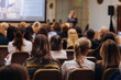 © tsuguliev - Female audience at the symposyum meeting, participants attendees in conference room hall listens to lecturer, group of women on a medical congress together listen to speaker on a stage at master-class