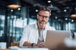 © ActionGP - Focused professional man with glasses working on a laptop in a modern office