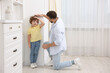 © New Africa - Father measuring his little son’s height near white wall at home. Space for text
