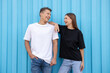 © New Africa - Young woman and man wearing blank t-shirts near light blue wall. Mockup for design