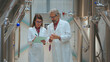 © Videophilia - Brewery quality control team members wearing lab coats, collaborating and inspecting samples in a craft beer production facility with large stainless steel tanks