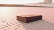 © icetray - A weathered book lies open on soft, golden sand dunes, bathed in the warm glow of a vibrant sunset. The fading light enhances the allure of the setting, sparking curiosity.