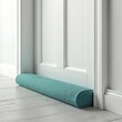 © miss irine - Turquoise soft door draft stopper on floor near white door. Home comfort with eco friendly textile draft excluder. Insulation from cold wind in apartment or house. Energy saving idea.
