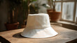 © utaem2022 - White bucket hat resting on wooden table with natural light and greenery in the background