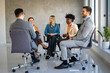 © NDABCREATIVITY - Diverse business people sitting in circle at group therapy session. Business coach training staff