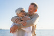 © Юлия Завалишина - Senior mature couple hugging enjoying outdoor recreation walking on beach. Old husband wife embracing with tenderness love enjoying sweet bonding. Grandmother grandfather together. Family moment love