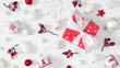 © prime1001 - Flat lay Christmas composition with red gift box, white ornaments, snowflakes, and berries on white background. Bright festive scene with cozy winter holiday atmosphere.