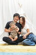 © Masakazu Tokashiki - A man and a woman are sitting with a baby in a tent. The baby is smiling and the man is holding the baby. The woman is wearing a white shirt and the man is wearing a black shirt