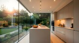 Modern minimalist kitchen bathed in warm golden hour sunlight flowing through a vast glass wall overlooking a lush garden.