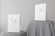 © Hasrizal - Blank shopping bag for branding, realistic white paper bag. Located on textured grey fabric. Isolated on grey background.
