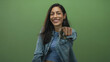 © Krakenimages.com - Woman points finger at camera in green studio wearing denim shirt and blue striped crop top; confidence empowerment.