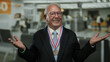 © Krakenimages.com - Senior man in business suit with medal standing indoors at airport, appearing confused, emphasizing travel and achievement.