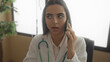 © Krakenimages.com - Hispanic woman doctor with stethoscope in clinic talking on phone indoors in hospital setting.