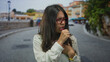© Krakenimages.com - Woman coughing outdoors on a city street wearing glasses and a watch expressing discomfort in a casual setting with blurred background vibrant scene.