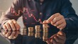 © AbdulMajid - Hand stacking coins with falling stock chart in background symbolizing loss, leadership conflict, business problem