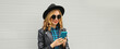 © rohappy - Stylish happy smiling modern young woman with phone, girl holding smartphone in black hat, jacket