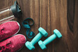 © O.Farion - Top view of pink sneakers, blue dumbbells, water bottle and measuring tape on wooden background with copy space, fitness equipment flat lay concept