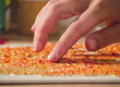 © light - An artist's fingers gently press small, colorful glass pieces into wet glue on an MDF board - Close-up of the handmade process of creating a detailed glass art mosaic