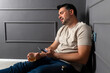 © Marko - Man sitting on floor with drink, struggling to stay awake in a dimly lit room