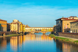 Colorful Ponte Vecchio bridge over Arno river with reflections on water and historic buildings in Florence city, Tuscany, Italy. Firenze old town. Italian architecture. Travel and touristic landmark