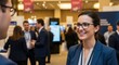 © Mario - Professional businesswoman smiling and networking at corporate conference event with people in formal attire discussing and exchanging ideas in modern exhibition hall setting