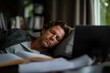 © AspctStyle - Tired man asleep on a couch beside an open laptop and scattered notebooks, depicting exhaustion and rest after working or studying in a cozy home office environment
