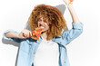 © VICHIZH - Happy young woman enjoying a slice of pizza, showcasing curly hair and casual denim outfit against a bright white background, symbolizing fun and indulgence